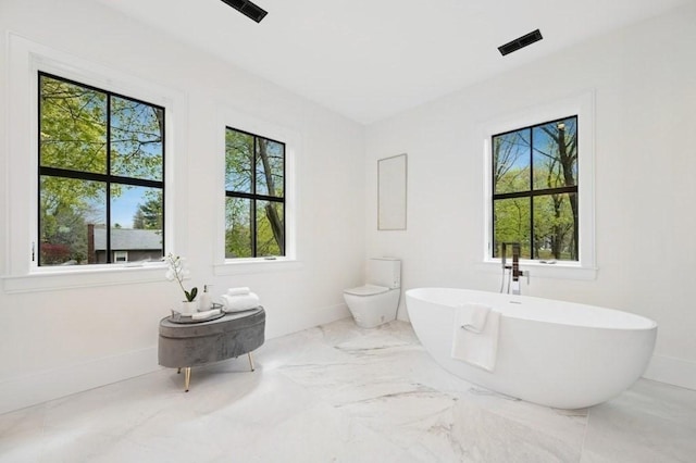 full bathroom with a soaking tub, baseboards, a healthy amount of sunlight, and marble finish floor