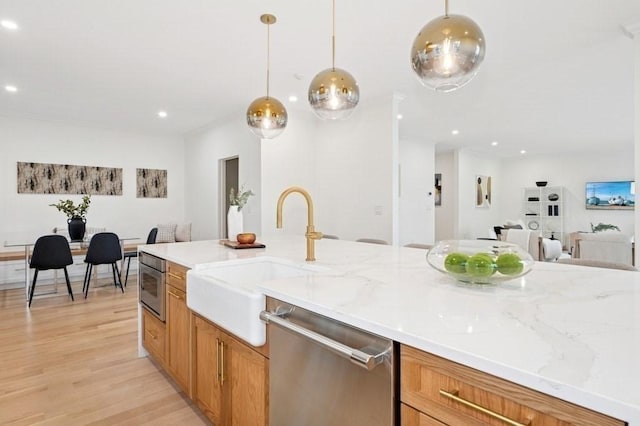 kitchen with light stone countertops, recessed lighting, a sink, light wood finished floors, and appliances with stainless steel finishes