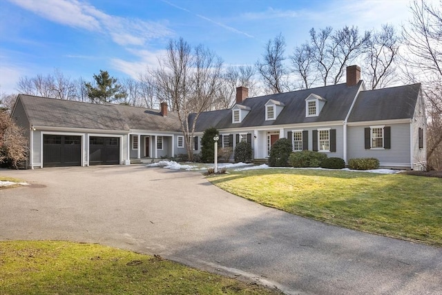 view of front of house with driveway, a chimney, a garage, and a front yard