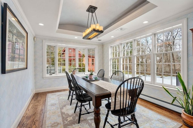 dining area with crown molding, baseboards, baseboard heating, wood finished floors, and a raised ceiling