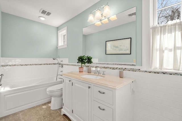 bathroom with tile walls, a garden tub, and visible vents