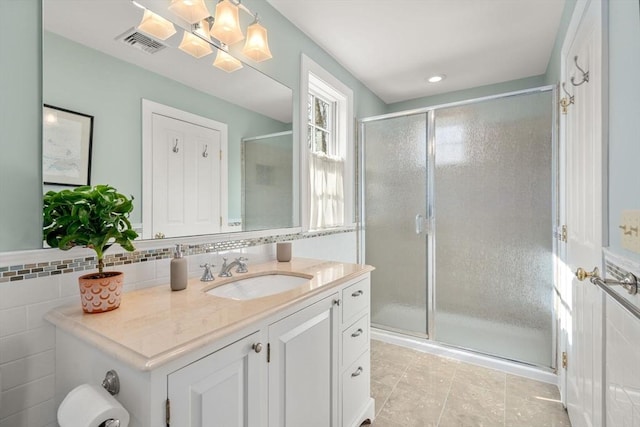 bathroom with tile patterned floors, visible vents, a stall shower, tile walls, and vanity