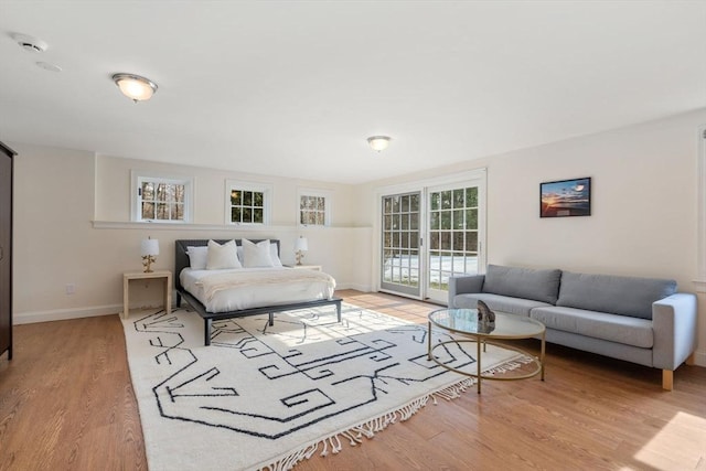 bedroom featuring baseboards, wood finished floors, and access to outside