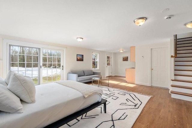 bedroom featuring baseboards, light wood-style floors, and access to exterior