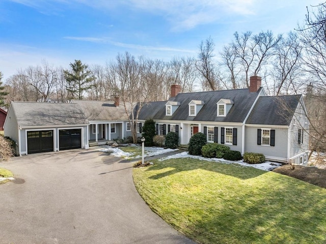 view of front of property featuring aphalt driveway, a front yard, a garage, and a chimney