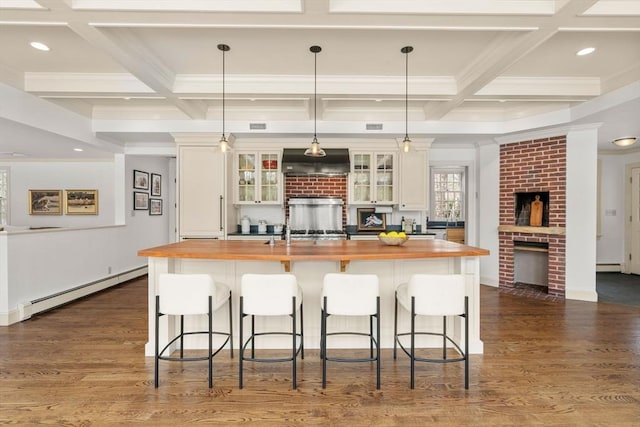 kitchen featuring a baseboard radiator, wooden counters, a brick fireplace, and custom range hood