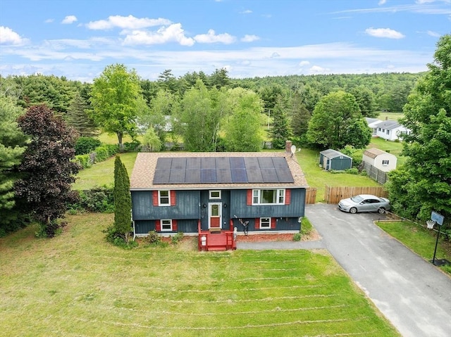 415 Holtshire Rd, Orange, MA 01364 - raised ranch with roof mounted solar panels, a front yard, a wooded view, a shingled roof, and a chimney