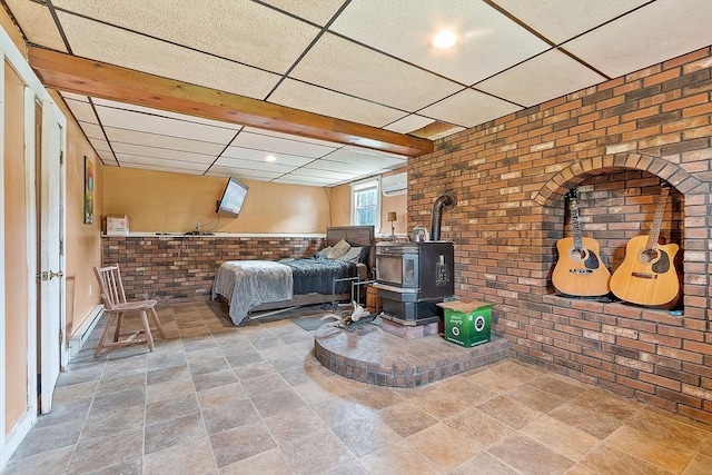415 Holtshire Rd, Orange, MA 01364 - bedroom with brick wall, a drop ceiling, a wood stove, stone finish flooring, and a baseboard radiator