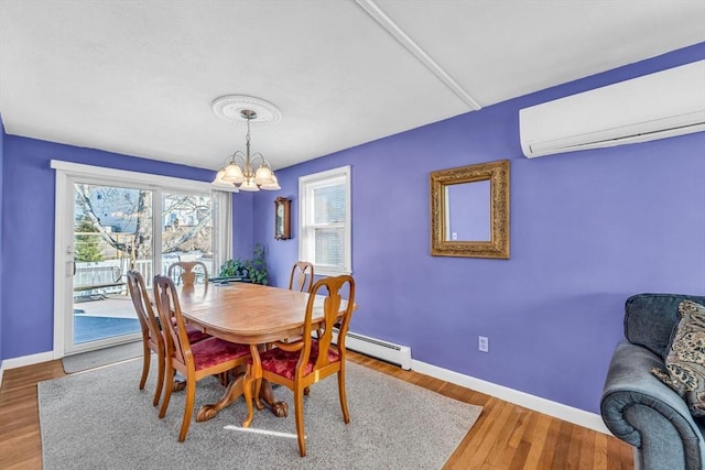 dining room featuring a baseboard radiator, an inviting chandelier, an AC wall unit, wood finished floors, and baseboards