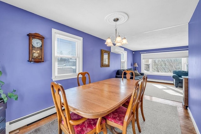 dining room with a baseboard heating unit, wood finished floors, a wall mounted AC, and a chandelier