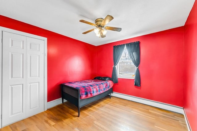 bedroom featuring a baseboard heating unit, ceiling fan, wood finished floors, and baseboards