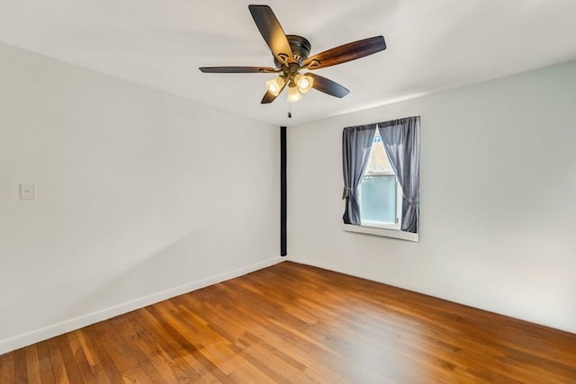 unfurnished room with a ceiling fan, baseboards, and wood finished floors