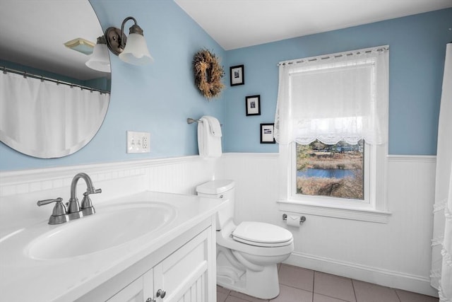 bathroom with toilet, wainscoting, vanity, and tile patterned floors