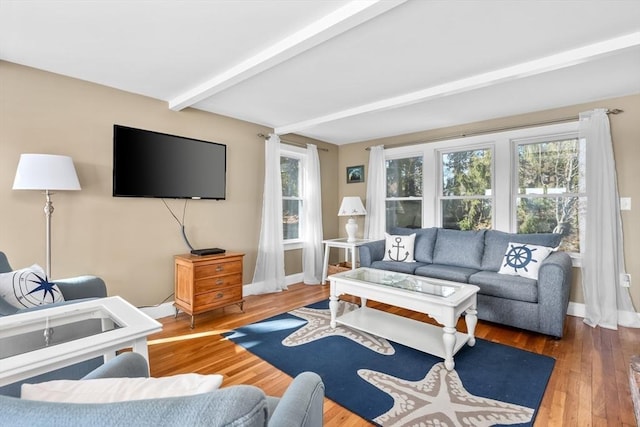 living area featuring beamed ceiling, baseboards, and wood finished floors