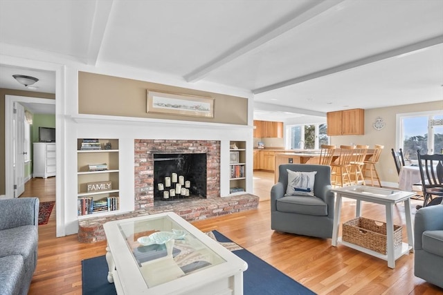 living area featuring beamed ceiling and light wood finished floors