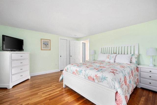 bedroom with light wood-style flooring, baseboards, and a closet