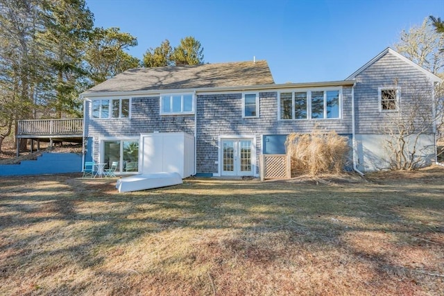 rear view of property featuring a deck, a lawn, and french doors