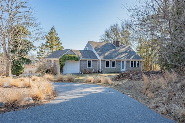 view of front facade with an attached garage, a chimney, and aphalt driveway