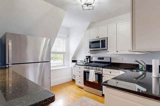 15 Garrison Rd, Brookline, MA 02445 - kitchen with stainless steel appliances, a sink, light wood-style flooring, white cabinets, and dark stone countertops