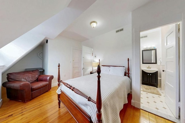 15 Garrison Rd, Brookline, MA 02445 - bedroom with light wood finished floors, connected bathroom, vaulted ceiling, and a sink