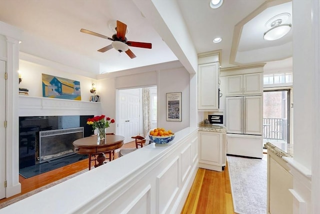 15 Garrison Rd, Brookline, MA 02445 - kitchen with a fireplace with flush hearth, a ceiling fan, light wood finished floors, a tray ceiling, and recessed lighting