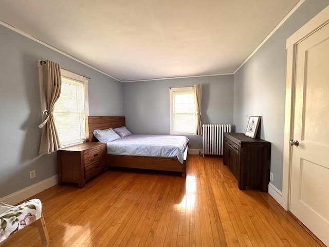 bedroom featuring radiator heating unit, light wood-style floors, ornamental molding, and baseboards