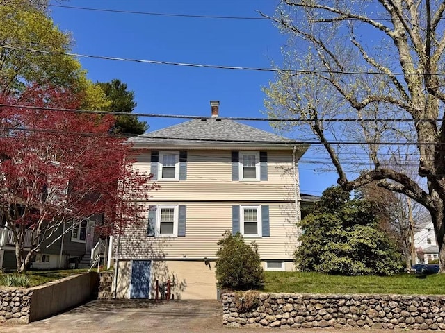 back of house with driveway, a shingled roof, and a garage