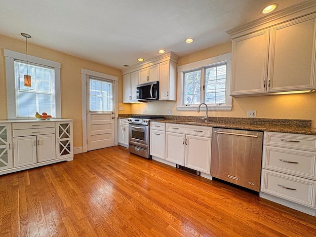 kitchen featuring recessed lighting, decorative light fixtures, appliances with stainless steel finishes, a sink, and light wood-type flooring