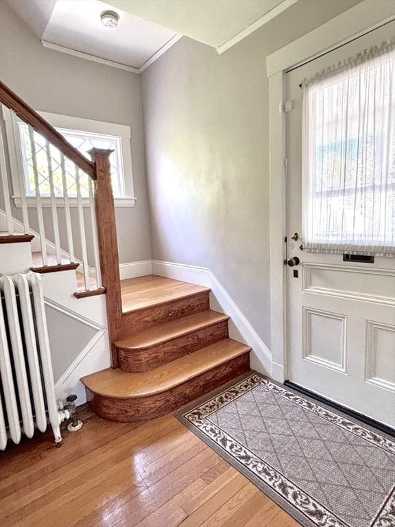 interior space featuring crown molding, stairway, baseboards, radiator, and wood finished floors