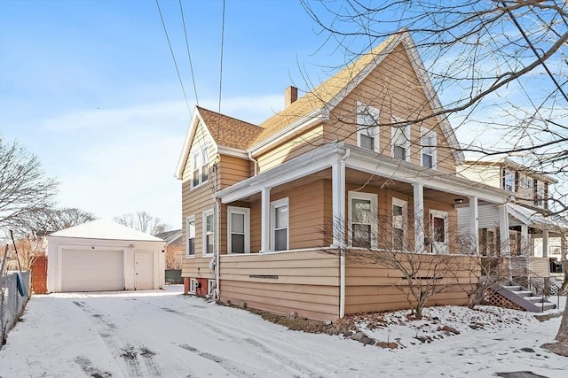 view of snow covered exterior with a garage, an outbuilding, and covered porch