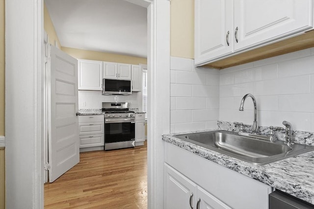 kitchen with light wood-type flooring, appliances with stainless steel finishes, white cabinets, and sink