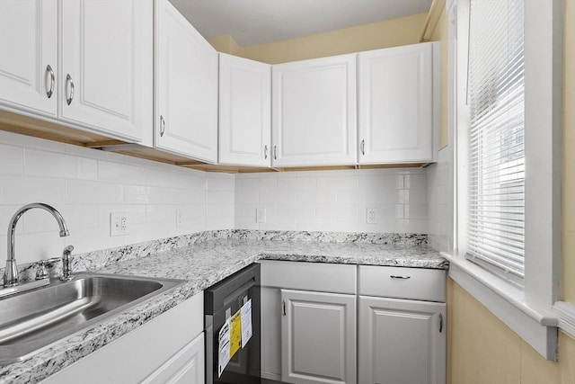 kitchen featuring tasteful backsplash, white cabinets, dishwasher, and sink