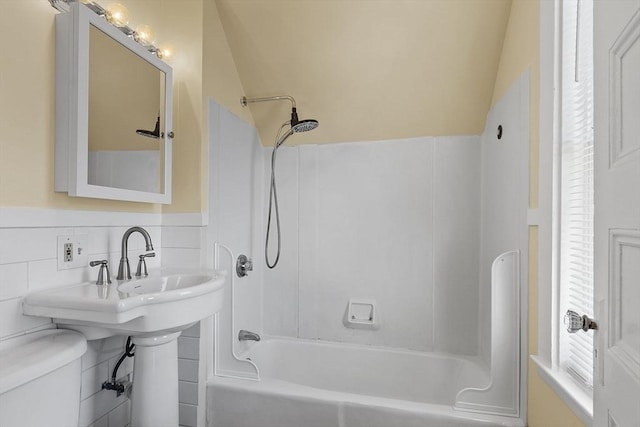 bathroom with vaulted ceiling, toilet, and shower / washtub combination