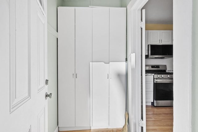 interior space with light wood-type flooring, appliances with stainless steel finishes, and white cabinetry