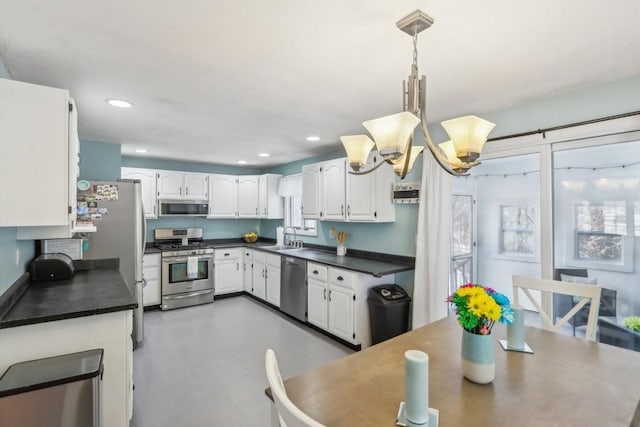 kitchen with pendant lighting, white cabinetry, stainless steel appliances, sink, and a notable chandelier