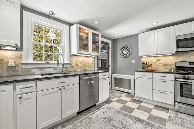 kitchen with dark countertops, white cabinets, stainless steel appliances, and a sink