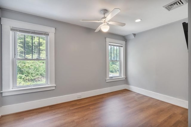 empty room with ceiling fan, plenty of natural light, crown molding, and hardwood / wood-style flooring