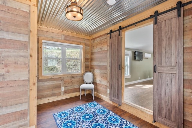 living area with hardwood / wood-style floors, a barn door, and wood walls