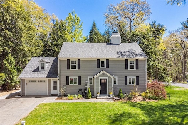 colonial home featuring concrete driveway, a garage, a chimney, and a front yard