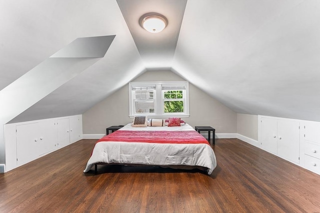 bedroom with vaulted ceiling, wood finished floors, and baseboards