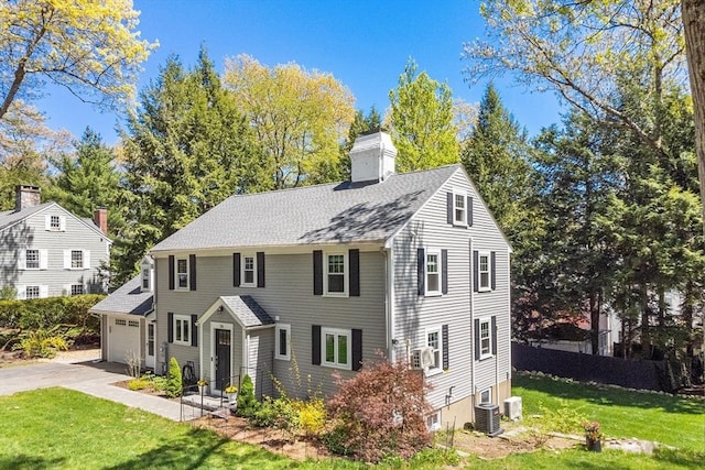 colonial home featuring driveway, a chimney, a front yard, and central AC