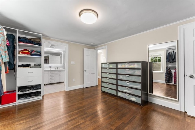 unfurnished bedroom featuring crown molding, connected bathroom, baseboards, and dark wood-type flooring