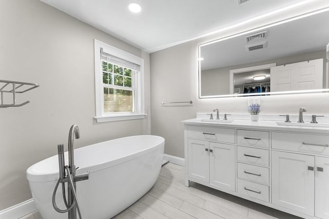 bathroom featuring double vanity, visible vents, baseboards, and a sink