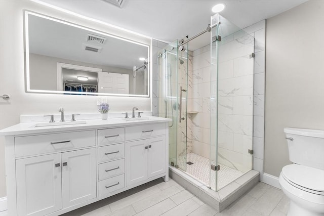 bathroom featuring double vanity, toilet, a stall shower, and a sink