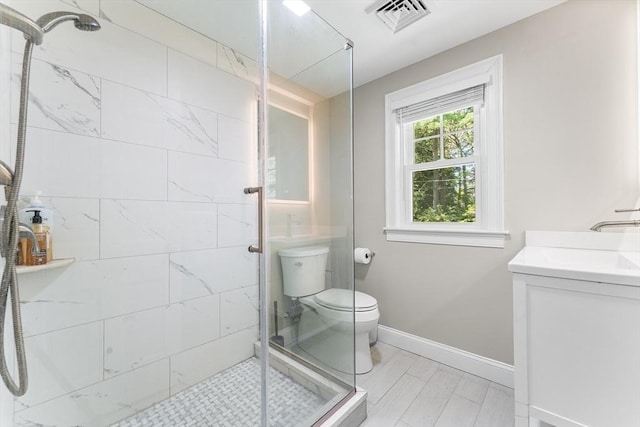 bathroom with a stall shower, toilet, baseboards, visible vents, and vanity