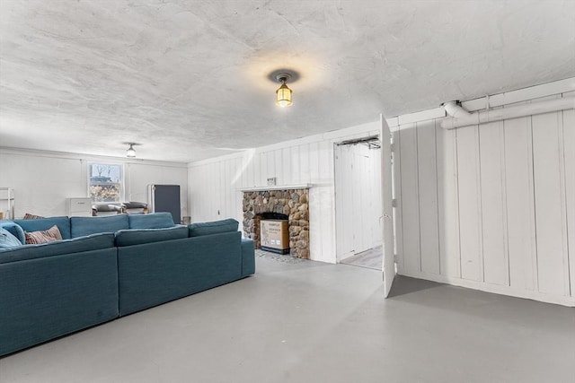 living area featuring finished concrete flooring and a stone fireplace