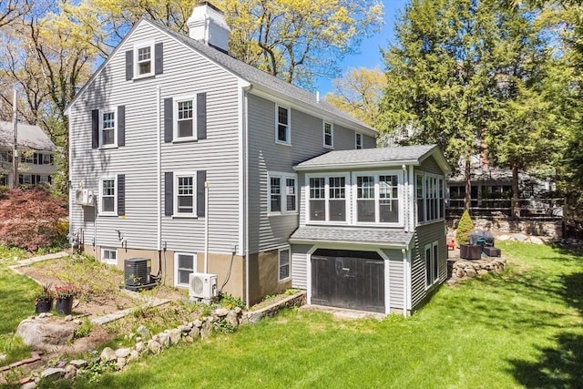 back of property with cooling unit, a chimney, a lawn, ac unit, and roof with shingles