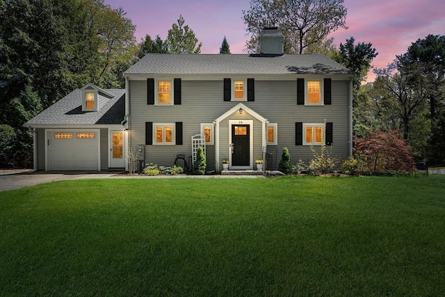 colonial home featuring driveway, a garage, a front lawn, a chimney, and a shingled roof