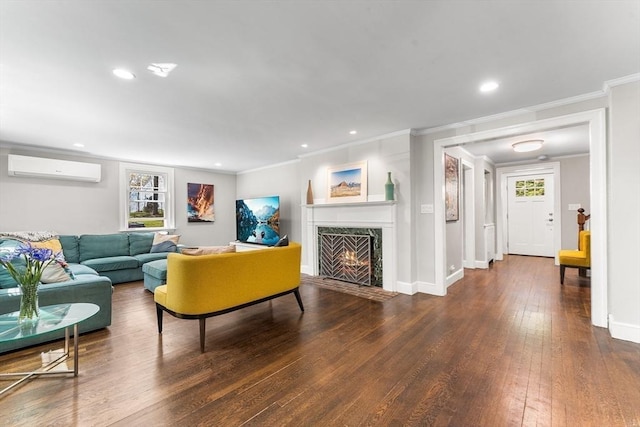 living room featuring a high end fireplace, hardwood / wood-style floors, ornamental molding, a wall mounted AC, and baseboards