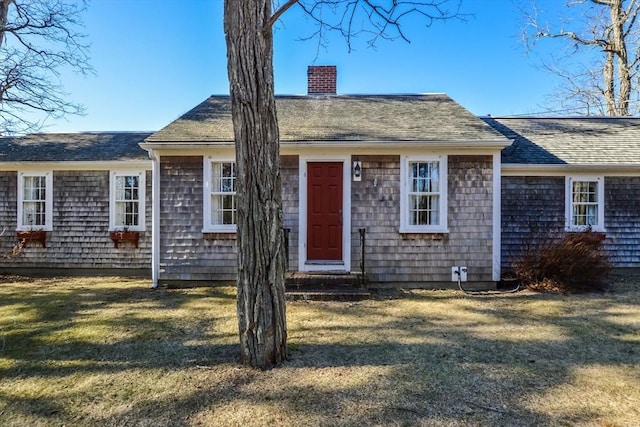 view of front of home featuring a front yard, roof with shingles, a chimney, and entry steps